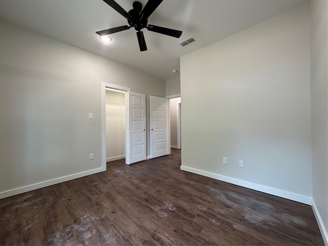 unfurnished bedroom with baseboards, a ceiling fan, dark wood finished floors, and visible vents