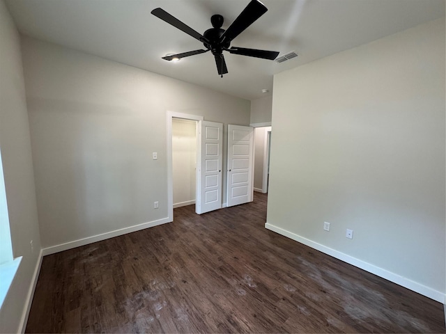 unfurnished bedroom with baseboards, a ceiling fan, dark wood-type flooring, and visible vents