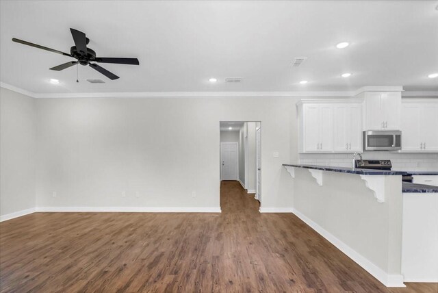 2377 Ridgley Dr, Flint, TX 75762 - kitchen featuring stainless steel appliances, white cabinets, dark wood-type flooring, a kitchen breakfast bar, and backsplash