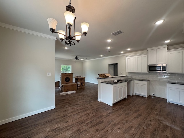 kitchen with crown molding, baseboards, stainless steel microwave, and white cabinetry