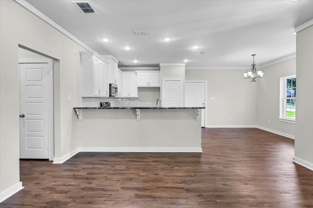 2377 Ridgley Dr, Flint, TX 75762 - kitchen featuring stainless steel microwave, a chandelier, ornamental molding, a peninsula, and white cabinetry