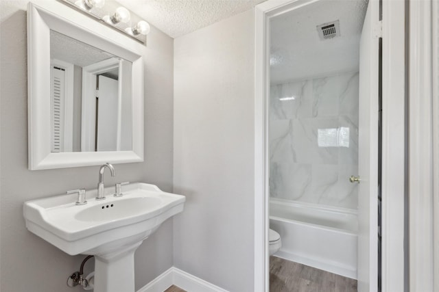 3931 Roma Ct, Rockwall, TX 75087 - full bath with a textured ceiling, toilet, wood finished floors, a sink, and shower / tub combination