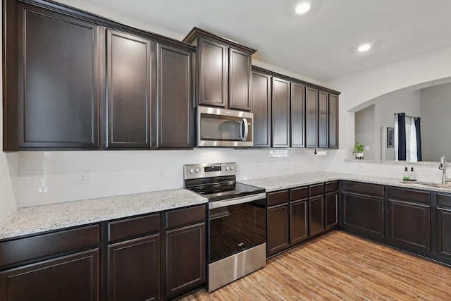 1616 Mackinac Dr, Crowley, TX 76036 - kitchen with a sink, stainless steel appliances, arched walkways, light wood-style floors, and tasteful backsplash
