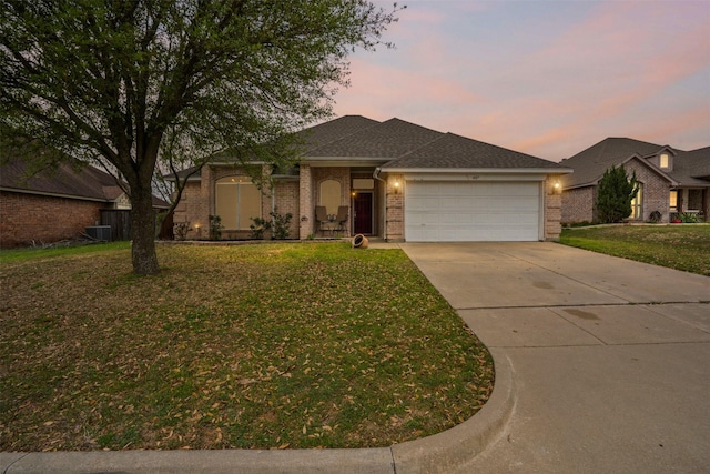 ranch-style home with driveway, cooling unit, a front yard, brick siding, and a garage