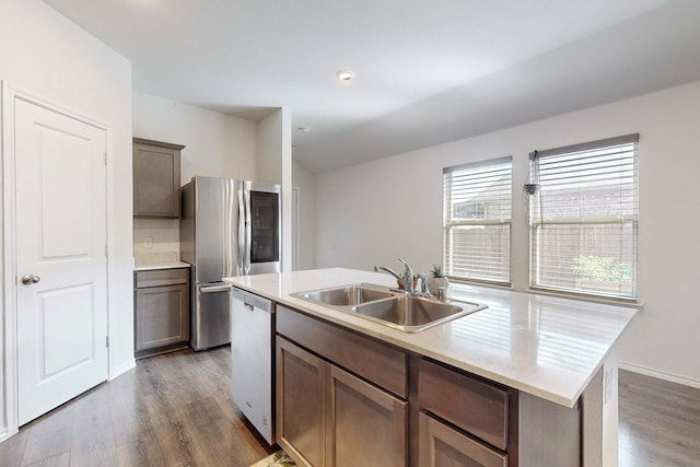 kitchen with a sink, a kitchen island with sink, appliances with stainless steel finishes, and wood finished floors
