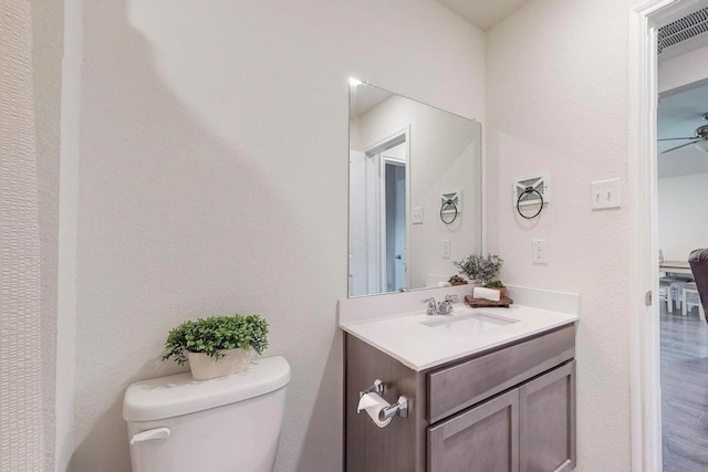 bathroom with wood finished floors, toilet, vanity, and a ceiling fan