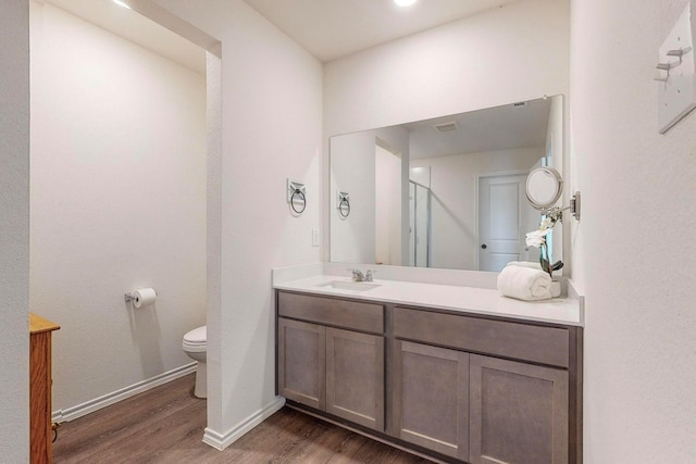 bathroom featuring baseboards, wood finished floors, toilet, and vanity