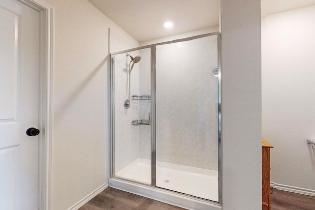 bathroom with baseboards, wood finished floors, and a stall shower