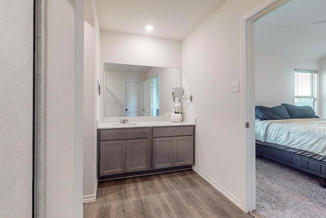 ensuite bathroom featuring baseboards, ensuite bath, wood finished floors, and vanity