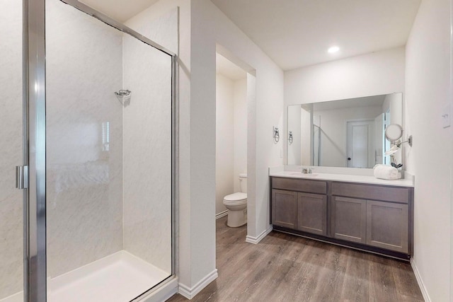 bathroom featuring a shower stall, toilet, wood finished floors, and vanity