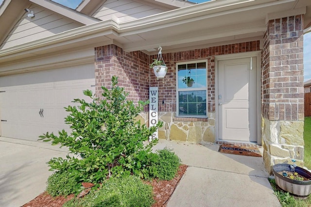 view of exterior entry featuring a garage and brick siding