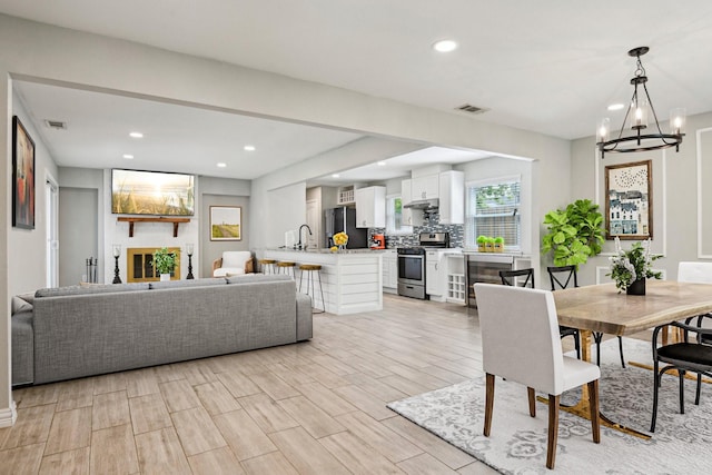 dining room featuring a chandelier, a large fireplace, light wood-style flooring, and recessed lighting