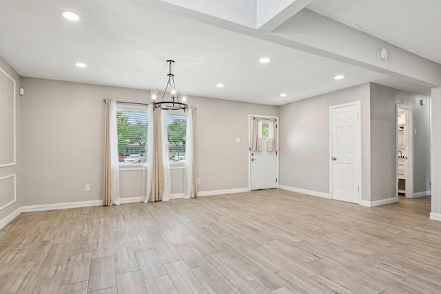 unfurnished living room featuring light wood-style floors, a chandelier, recessed lighting, and baseboards