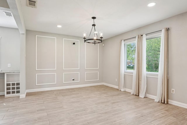 unfurnished dining area featuring a chandelier, light wood-style floors, recessed lighting, and baseboards