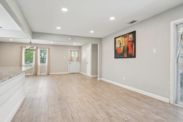 unfurnished living room featuring recessed lighting, light wood-style floors, baseboards, and a chandelier