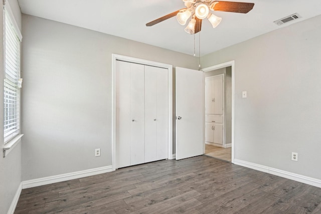 unfurnished bedroom with wood finished floors, multiple windows, and a closet