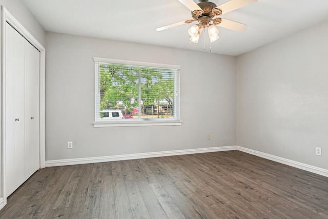 unfurnished bedroom featuring wood finished floors, baseboards, a closet, and a ceiling fan