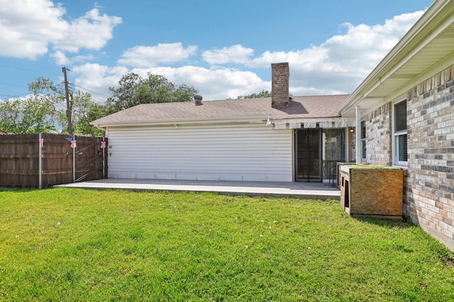back of property with a chimney, a patio, and roof with shingles