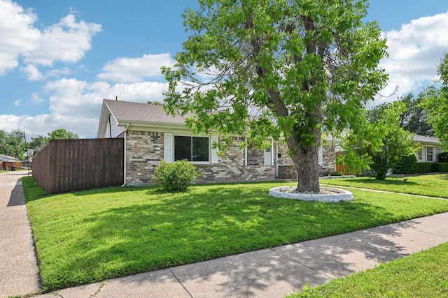 obstructed view of property featuring a front lawn and brick siding