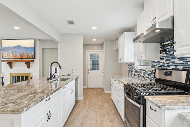 kitchen featuring stainless steel appliances, under cabinet range hood, a sink, baseboards, and light wood-style flooring