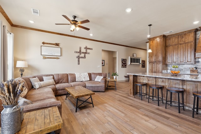 living area featuring a ceiling fan, light wood finished floors, ornamental molding, visible vents, and recessed lighting
