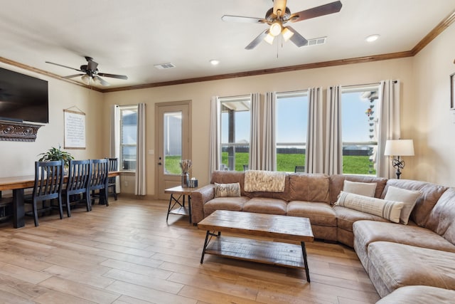 living room featuring light wood-type flooring, a ceiling fan, visible vents, and crown molding