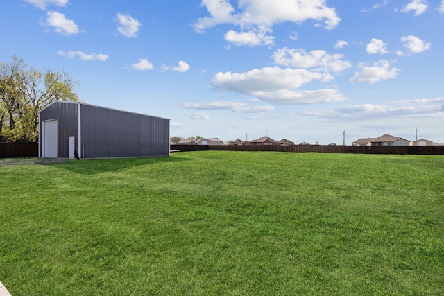 view of yard with fence, an outbuilding, and a detached garage