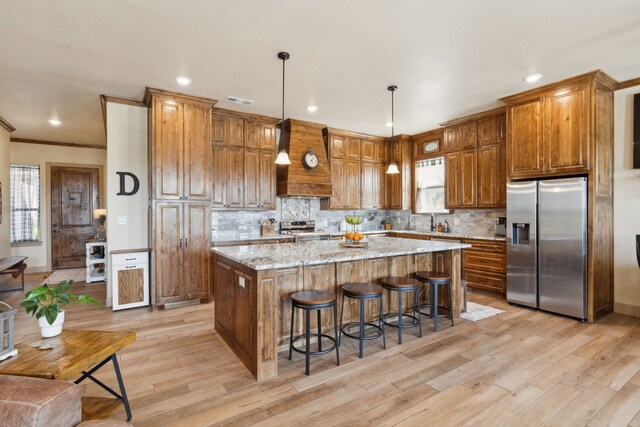 kitchen featuring light wood-type flooring, a kitchen island, appliances with stainless steel finishes, and a breakfast bar area
