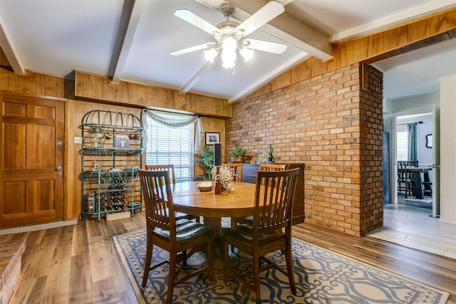 dining room with brick wall, wood walls, light wood-style flooring, and a wealth of natural light