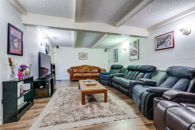 living room featuring beamed ceiling, light wood-type flooring, and a textured ceiling