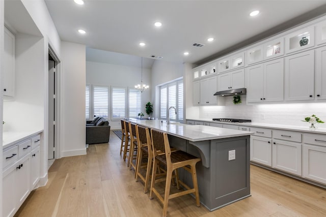 1716 Bradford Pear Way, Celina, TX 75078 - kitchen featuring decorative backsplash, a kitchen island with sink, under cabinet range hood, a breakfast bar area, and a chandelier