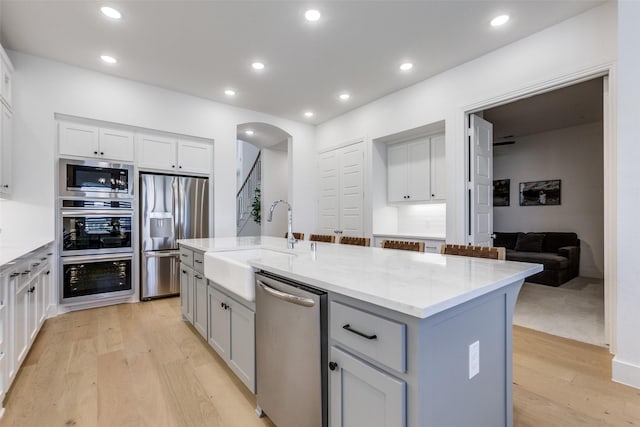 1716 Bradford Pear Way, Celina, TX 75078 - kitchen featuring appliances with stainless steel finishes, a sink, light wood-style flooring, gray cabinetry, and light stone countertops
