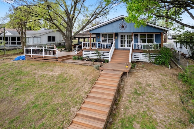 view of front of property with fence, a wooden deck, a sunroom, and a front lawn