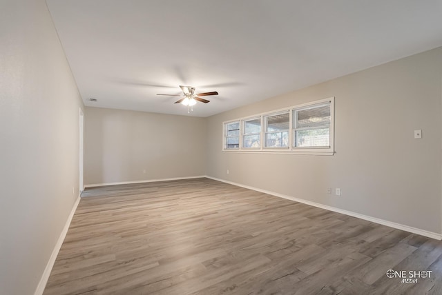 spare room featuring a ceiling fan, wood finished floors, and baseboards