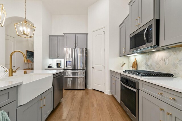 kitchen featuring gray cabinetry, a sink, and appliances with stainless steel finishes