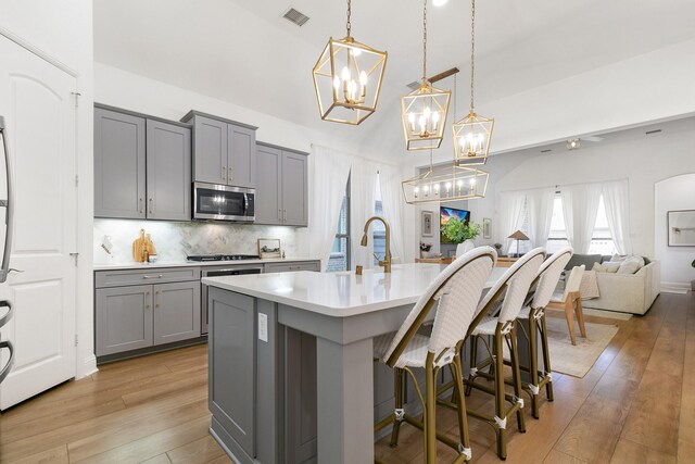 5108 Shallow Pond Dr, Little Elm, TX 76227 - kitchen featuring gray cabinets, stainless steel microwave, light countertops, open floor plan, and a chandelier