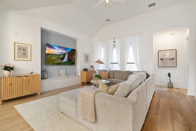 living room featuring visible vents, arched walkways, vaulted ceiling, wood finished floors, and a ceiling fan