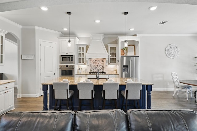 kitchen with decorative backsplash, white cabinets, visible vents, custom exhaust hood, and appliances with stainless steel finishes