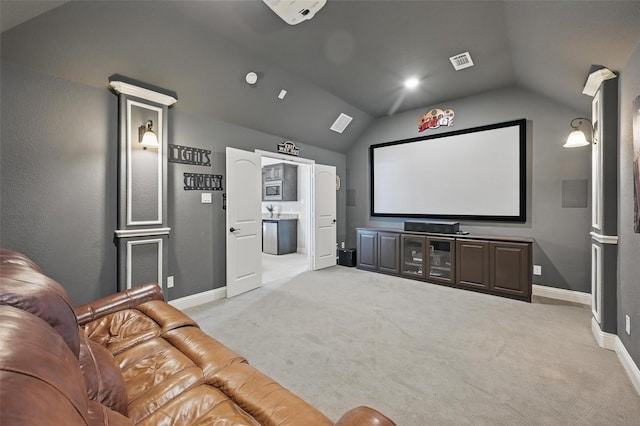 carpeted home theater room featuring baseboards, lofted ceiling, and visible vents