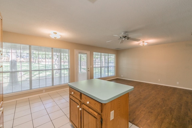 2111 Meadowview Dr, Keller, TX 76262 - kitchen featuring light countertops, a kitchen island, baseboards, brown cabinetry, and ceiling fan