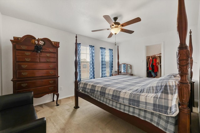 bedroom with a ceiling fan, a closet, a walk in closet, light colored carpet, and baseboards