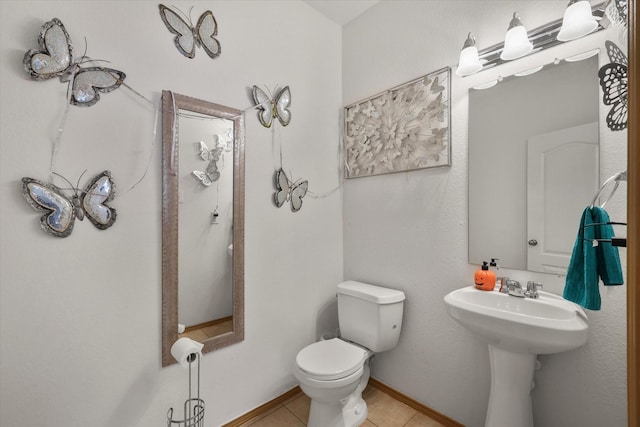 half bath featuring toilet, tile patterned floors, and a sink