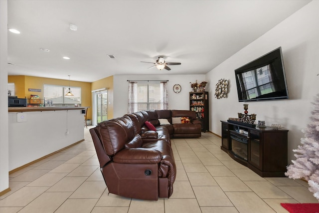 living area featuring a wealth of natural light, ceiling fan, and light tile patterned floors