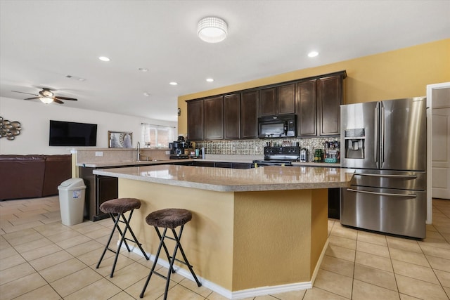 kitchen with light tile patterned floors, a center island, dark brown cabinetry, and black appliances