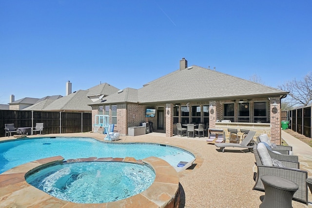 view of pool featuring a patio, fence, and a pool with connected hot tub