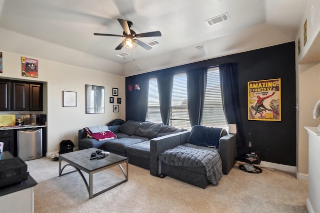 living area featuring visible vents, a ceiling fan, and light carpet