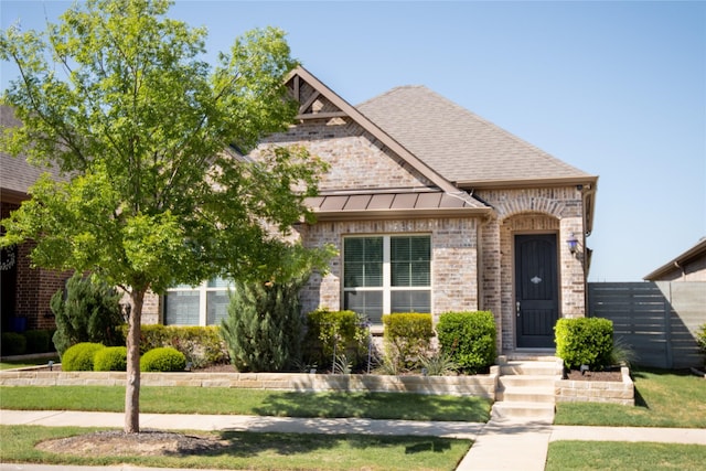 view of front facade featuring a standing seam roof, roof with shingles, and brick siding