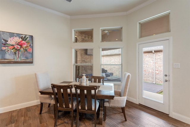 dining space featuring baseboards, crown molding, and wood finished floors