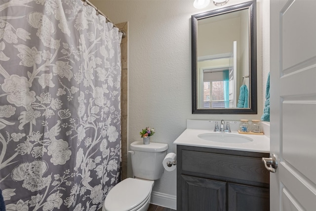 bathroom featuring a textured wall, curtained shower, vanity, and toilet