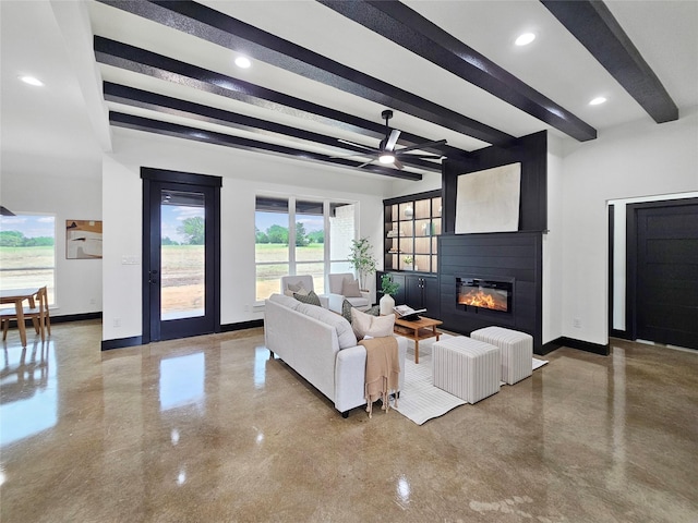 living room with baseboards, a fireplace, a ceiling fan, beam ceiling, and concrete flooring